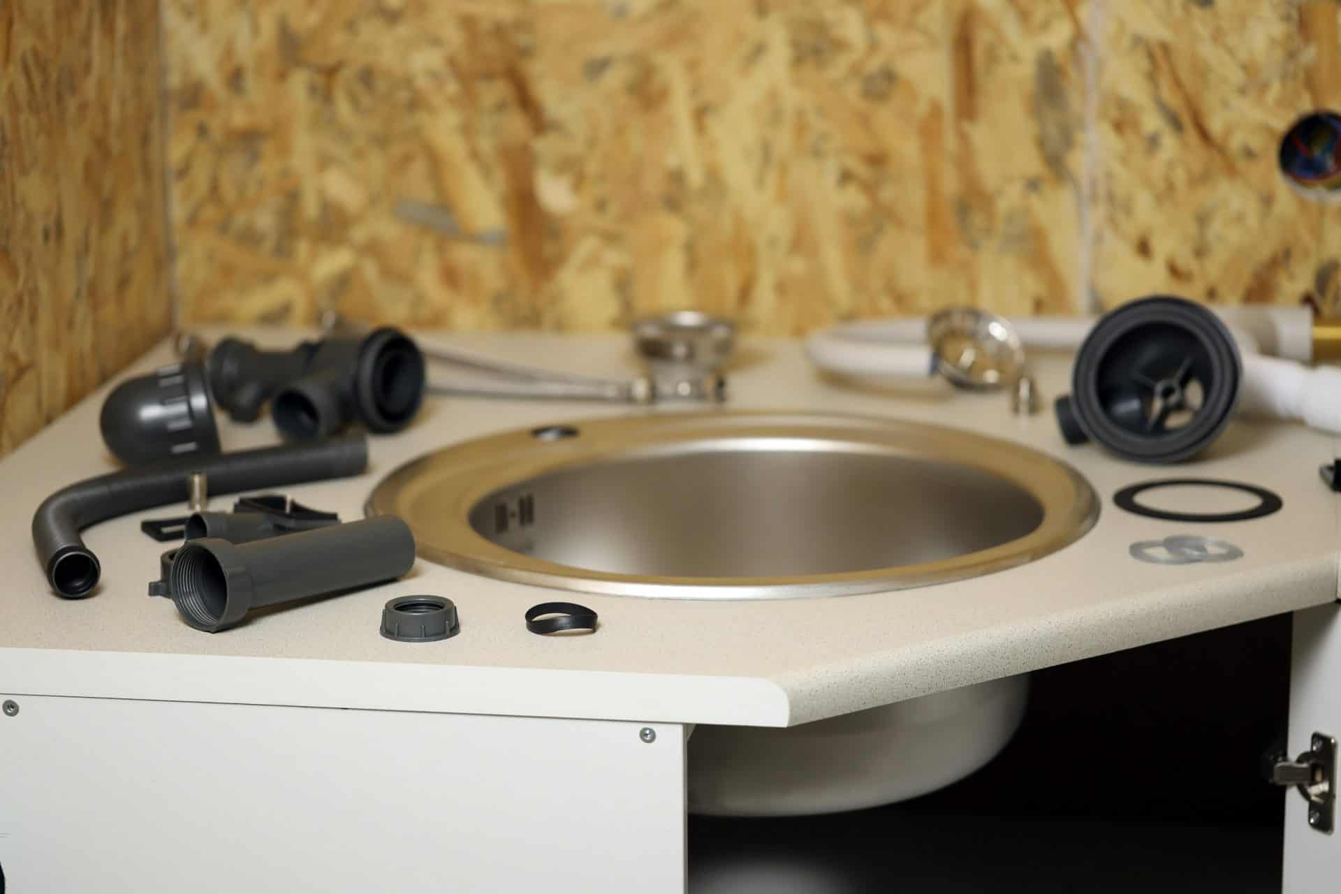 Plumbers tools and water tap ready for installation near sink on countertop in kitchen. Connections for the installation of the water faucet for the kitchen sink