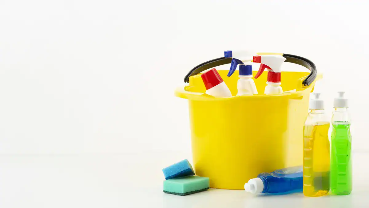 Yellow bucket holding household cleaning sprays and detergents