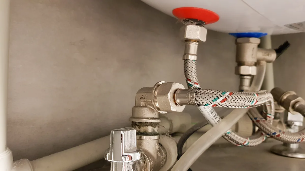 Hot and cold water connections with braided hoses under a water heater
