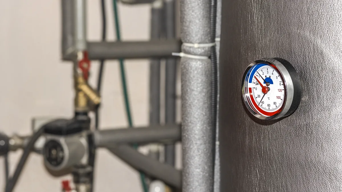 Temperature gauge on an insulated hot water storage tank with pipes and valves