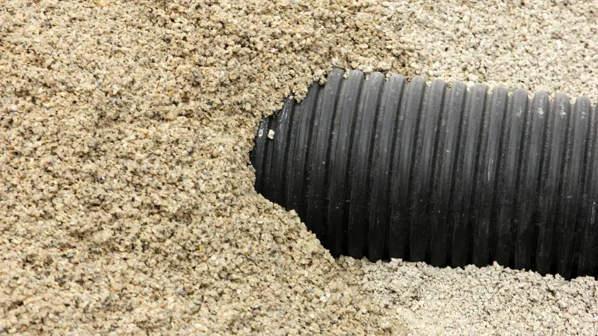 Black corrugated drainage pipe bedded in drainage gravel