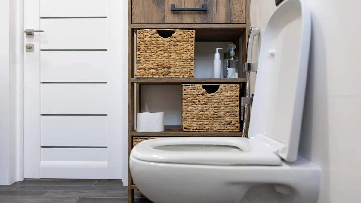 White close-coupled toilet with the lid up in a small bathroom